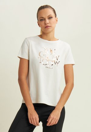 T-shirt en coton blanc avec un graphique réfléchissant "TU BRILLES AUJOURD'HUI". Manches courtes, col rond, coupe décontractée. Associé à un pantalon noir.