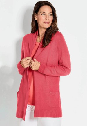Koraalgebreide cardigan met lange mouwen, geribde manchetten, open voorkant en twee opgestikte zakken. Zachte textuur en een losse pasvorm.