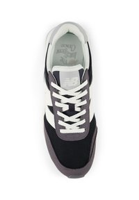 Musta ja harmaa urheilukenkä, jossa on verkkomateriaali, valkoiset yksityiskohdat ja pyöreät nauhat. Varustettu pehmustetulla nilkkaremmillä ja teksturoidulla pohjalla.