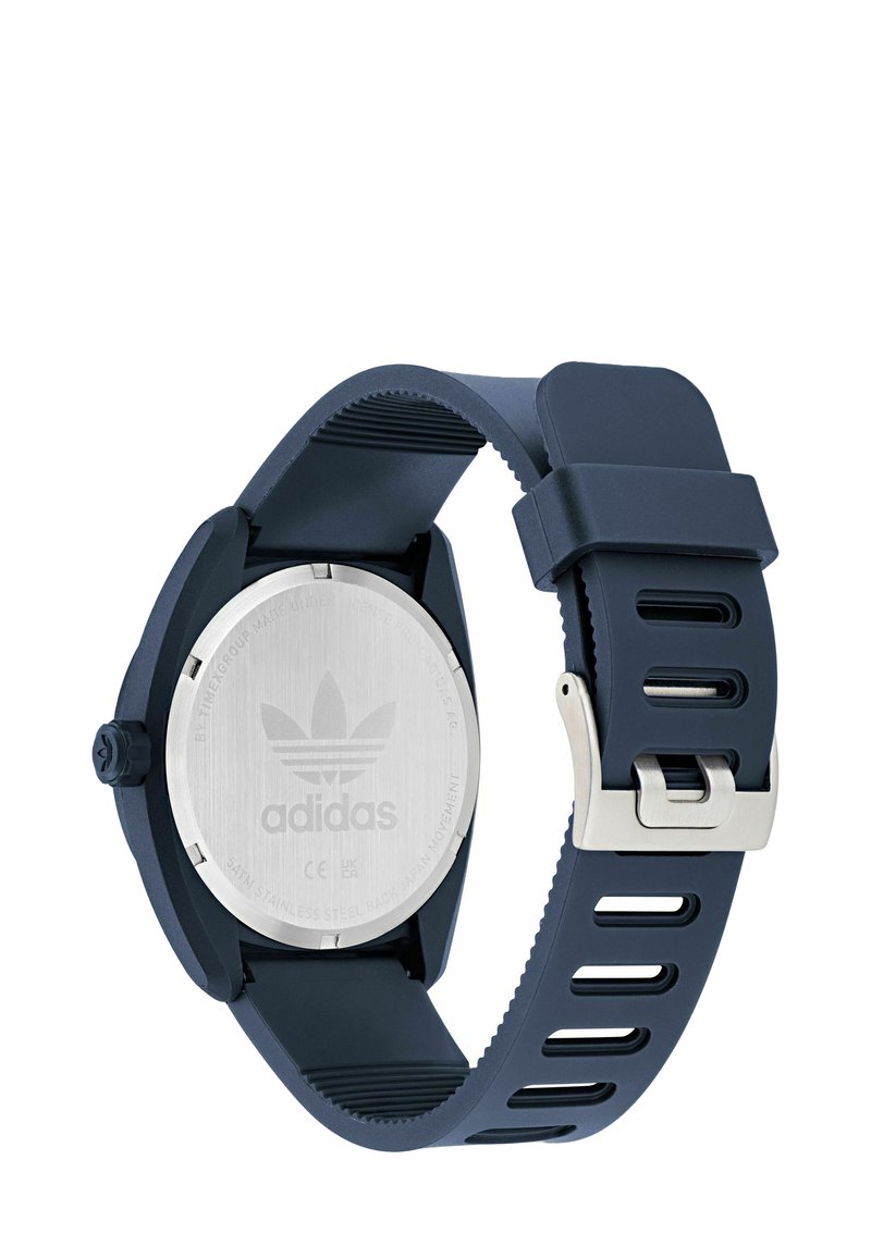Montre-bracelet Adidas bleu foncé montrant un dos en acier inoxydable avec logo et un bracelet en caoutchouc réglable avec boucle.