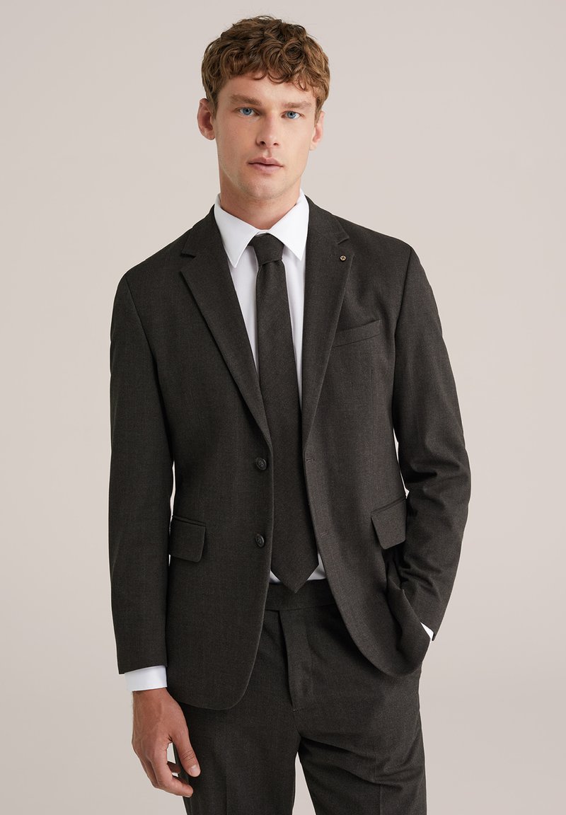 Ogļu pelēks uzvalks ar strukturētu dizainu, kuram ir žakete ar vienu pogu, ieliektu apkakli un saskanīgu kaklasaiti. Tekstūra audums un krūšu kabata.
