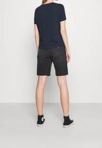 Námořnické tričko s krátkým rukávem, doplněné černými džínovými šortkami s třepenými lemy a zadními kapsami, a černými vysokými teniskami.