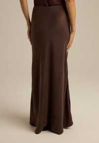 Długa brązowa spódnica wykonana z gładkiego materiału, z przylegającym stanem i rozszerzanym dołem, z delikatnym połyskiem i bez widocznych wzorów czy zdobień.