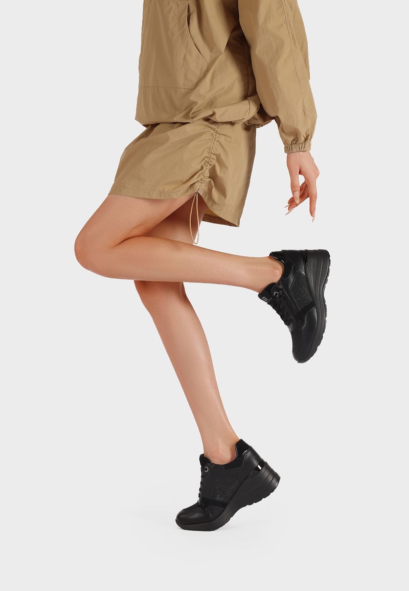 Sneaker nere con suola spessa, caratterizzate da una combinazione di materiali texture e pannelli in mesh. Il design presenta un sistema di chiusura con lacci e accenti discreti.