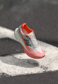 Chaussure de course au design léger, tige grise et rose, semelle intermédiaire blanche et surface texturée. Dotée d'un logo et de lacets pour un maintien sécurisé.