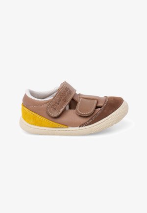 Zapato para niño pequeño marrón y amarillo con tiras de velcro y suela de goma blanca, lados abiertos para ventilación.