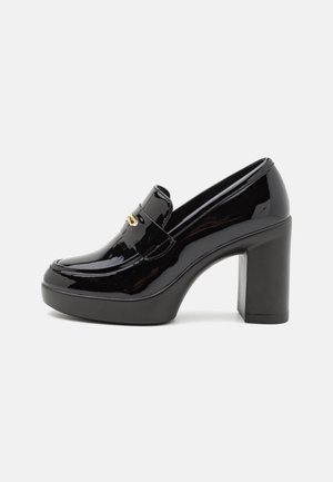 Mocassin à talons hauts en cuir verni noir avec semelle à plateforme, bout arrondi et accent doré à l'avant. Fini lisse et brillant.