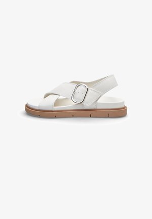Sandalo bianco open-toe con cinturini incrociati, fibbia argento, cinturino posteriore e suola piatta marrone chiaro.