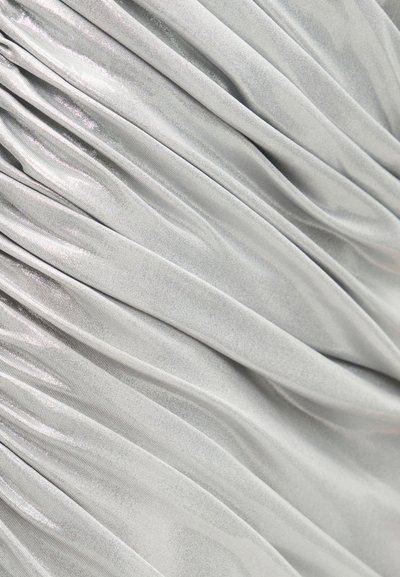 Απαλό, ασημί-γκρι ύφασμα με ομαλές, διαγώνιες πιέτες που δημιουργούν ήπιες πτυχώσεις και μια διακριτική λάμψη στην επιφάνεια.