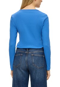 Langsleeve blauwe top van katoen, met een ronde halslijn en een aansluitend ontwerp, gecombineerd met high-waisted blauwe spijkerbroeken met zakken.