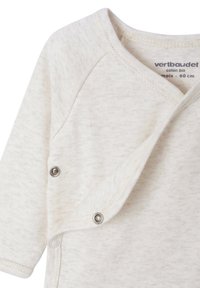 Weißes, strukturiertes Baumwoll-Overall mit langen Ärmeln, einemÜberlappungs-Design vorne und Druckknöpfen an der Seite für ein einfaches Ankleiden.