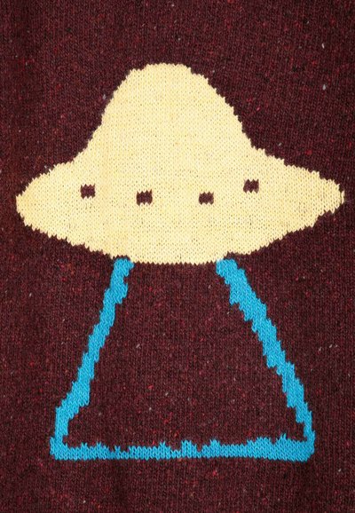 Design tricoté d'un OVNI jaune avec quatre fenêtres noires et un faisceau bleu sur un fond en tissu rouge foncé.