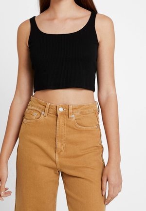 Czarny prążkowany krótki top na ramiączkach, zestawiony z dżinsami w kolorze karmelowym o wysokim stanie, z zapięciem na guzik i przednimi kieszeniami.