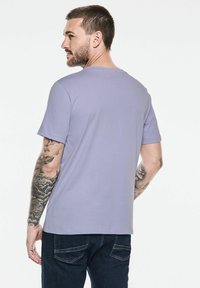 T-shirt à manches courtes, col rond, en lavande clair, fabriqué en tissu doux. Présente une coupe décontractée et des détails de couture subtils.