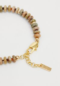 Bracciale multicolore in perline con pietre circolari lisce, dotato di una chiusura dorata e un'etichetta incisa, che presenta un design testurizzato.