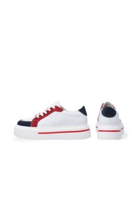 Weiße Sneaker mit roten und marineblauen Wildlederakzenten, perforierten Seiten und einer dicken weißen Sohle mit rotem Streifen. Rundliche Spitze und Schnürdesign.