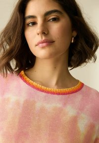 Rosa Batikpullover mit rundem Ausschnitt; verfügt über eine strukturierte, mehrfarbige Borte in Orange, Pink und Gelb. Weiches Strickmaterial.