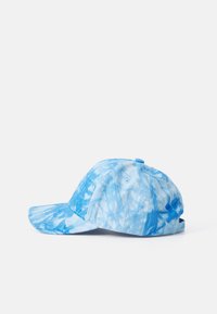 Blå tie-dye caps med bøyd skjerm, laget av stoff med en teksturert finish. Har ventilasjonsøyler og en justerbar bakre stropp.