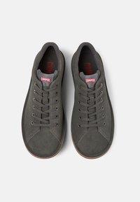 Gray suede sneakers with a rounded toe, flat laces, and red "Camper" logo. Rubber sole and textured panels are visible.