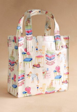 Kremowa torba na ramię z ilustracjami psów, krzeseł, stosów złożonych ubrań oraz wazonów z kwiatami w pastelowych kolorach.