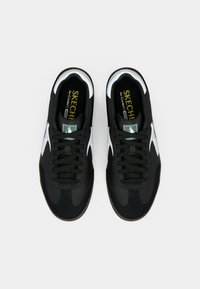 Black athletic shoes with a smooth texture, white accents, and black laces. Features a cushioned insole labeled "Air-Cooled."