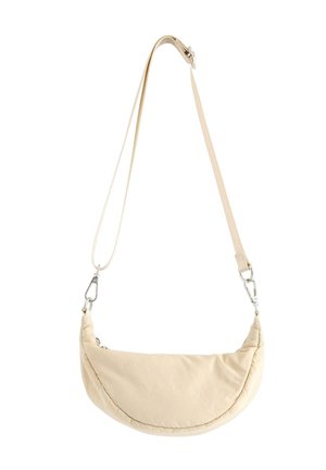 Béžová půlměsíčková taška přes rameno s nastavitelným popruhem a stříbrnými kovovými přezkami na bílém pozadí.