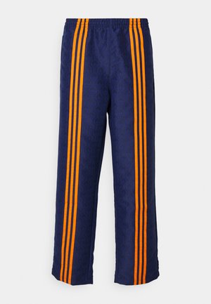 Tumesinised püksid, millel on kogu pinnal mustriline tekstuur ja igal küljel kolm julget oranži triipu. Ülal elastne vöökoht.