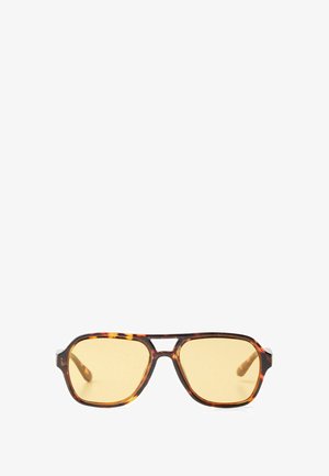 Skildpaddemønstrede solbriller med et geometrisk design, gule linser og metal detaljer på stængerne. Bredt stel og mat overflade.