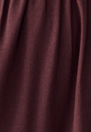 Mīksts, adīts burgundijas krāsas audums ar maigiem vertikāliem lokiem un gludu, vienmērīgu tekstūru.