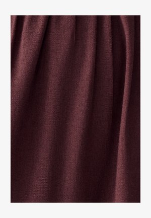 Mīksts, adīts burgundijas krāsas audums ar maigiem vertikāliem lokiem un gludu, vienmērīgu tekstūru.