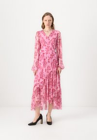 Robe maxi fleurie rose avec manches longues, design croisé et ourlet asymétrique. Fabriquée en tissu transparent avec des volants et une taille cintrée.