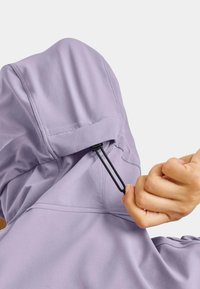 Light purple hoodie features a pull string at the neck. The fabric appears soft with visible stitching accents. Hand gripping the string.