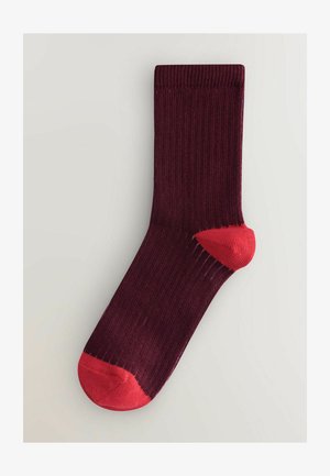 Burgundi värvi sokid ribikonstruktsiooniga, millel on erks punane kann ja varvas. Keskmise säärme pikkusega, ilma seameta ehitus. Sile kangas.
