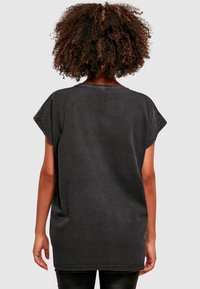 Svart oversized t-skjorte med korte ermer, avslappet passform, synlige sømdetaljer og myk, teksturert stoff.