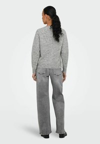 Grå stickad tröja med långa ärmar och ribbat nederkant, kombinerad med högmidjade grå jeans med rak benlinje och minimal dekoration.