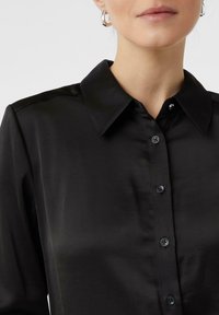 Black long-sleeve shirt with a classic collar, made of smooth fabric, featuring button closure and subtle button accents.