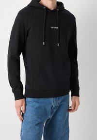 Czarna bluza z kapturem z przednią kieszenią, z małym białym logo „LES DEUX” na klatce piersiowej. Wykonana z miękkiego materiału z ściągaczami na mankietach.