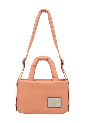 Ferskenfarget bag laget av polstret materiale med doble håndtak og en lang, justerbar stropp. Har et sølvfarget logo-patch på den ene siden.