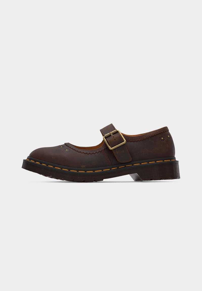Dark brown leather Mary Jane shoe with brass buckle, scalloped edges, floral perforations, and thick rubber sole with yellow stitching.