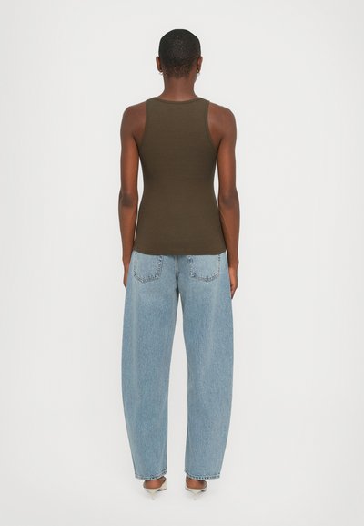 Olijfgroene aansluitende tanktop met een klassiek ontwerp, gecombineerd met lichtblauwe wijde jeans met achterzakken en denimtextuur.