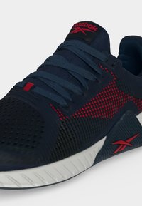 Σπορ παπούτσι Reebok σε ναυτικό μπλε και κόκκινο χρώμα με υφασμάτινο επάνω μέρος με υφή, επενδεδυμένο γιακά, ναυτικομπλε κορδόνια και λευκή σόλα με κόκκινη λεπτομέρεια λογότυπου.