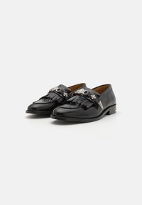 Mustad nahast loafers frangeeritud detailide ja hõbedaste aksessuaaridega. Ümar nina ja madal kuhi konts. Ühtlane sile pind.