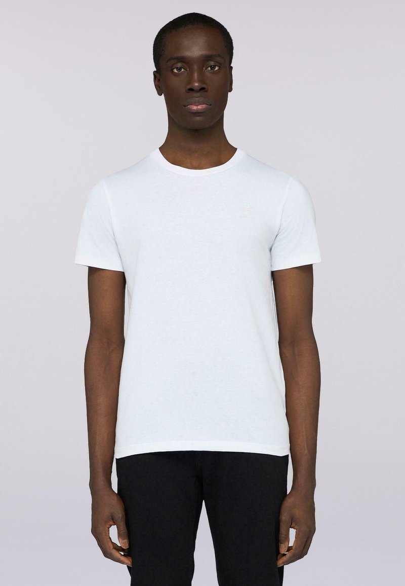 Bílá bavlněná tričko s kulatým výstřihem, krátkými rukávy a decentním logem na levé hrudi. V kombinaci s černými džíny.