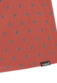 Tissu rouge présentant un motif répétitif de petites lettres "P" noires. Comprend une étiquette noire avec un texte blanc indiquant "Pockies Couch Couture."