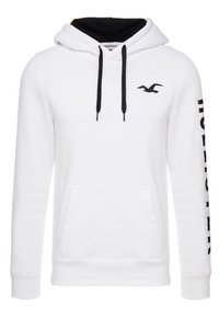 Vit hoodie med svarta detaljer, utformat med en framficka, snörningar och en logotyp på bröstet samt design längs ärmen. Mjuk material.