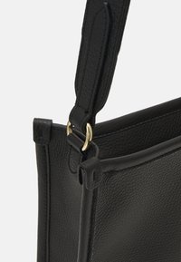 Borsa a mano in pelle nera con superficie testurizzata, dettagli in hardware dorato e tracolla regolabile, che mette in mostra un design strutturato.