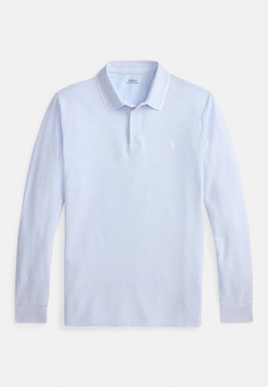 Gaiši zilas krāsas polo krekls ar garām piedurknēm, apkakli, pogu aizdari un mazu baltu izšūtu logotipu krūtīs.