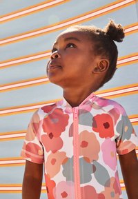 Kurzärmeliges Rashguard mit rosa Blumenmuster in Rot, Pfirsich und Grau; ausgestattet mit einem Frontreißverschluss und einem runden Ausschnitt.