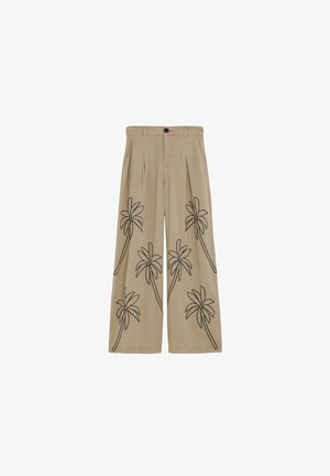 Pantalones de pierna ancha beige con patrones de palmeras delineados en negro en el frente, con trabillas para cinturón, botón delantero y pliegues debajo de la pretina.