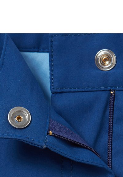 Un tissu bleu à la texture lisse présente un bouton-pression argenté et une poche zippée cachée avec des accents dorés, mettant en avant un design pratique.